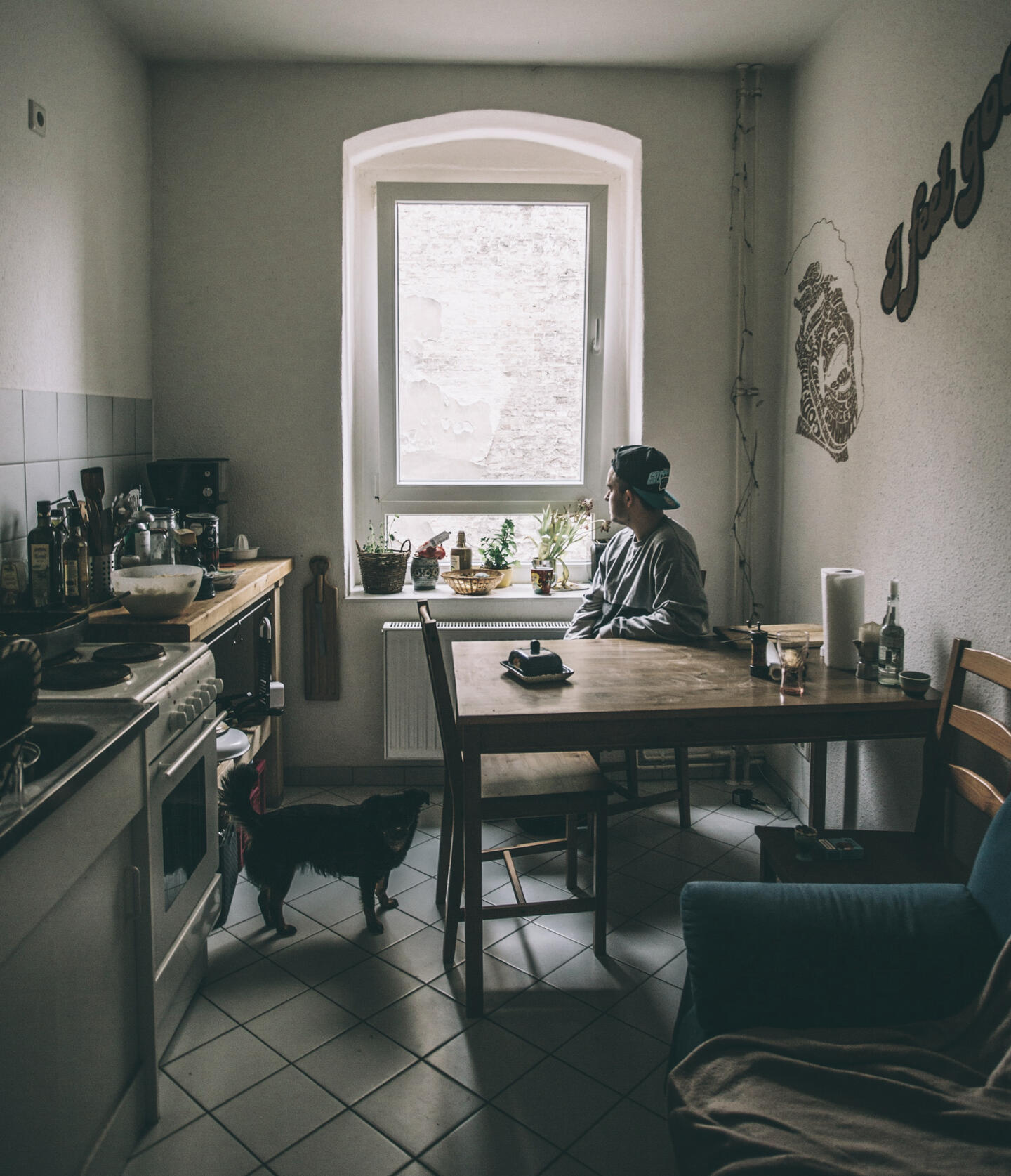 A man at a kitchen table looking out a window in early morning light